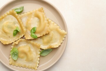 Delicious ravioli with basil on light table, top view. Space for text
