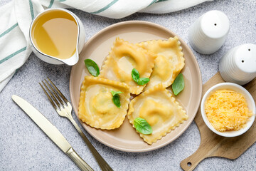 Delicious ravioli with basil served on light grey table, flat lay
