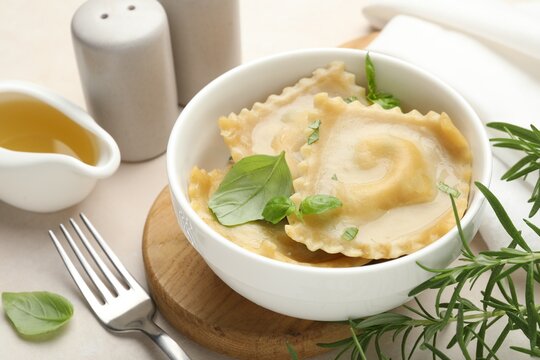 Delicious ravioli with basil served on light table, closeup
