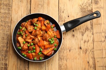 Delicious cooked stew in frying pan on wooden table, top view