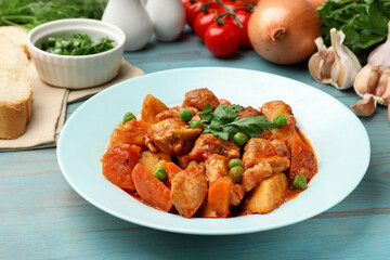 Delicious cooked stew and ingredients on light blue wooden table, closeup