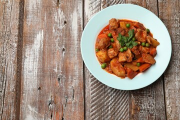 Delicious cooked stew on wooden table, top view. Space for text
