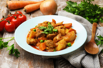 Delicious cooked stew and ingredients on wooden table, closeup