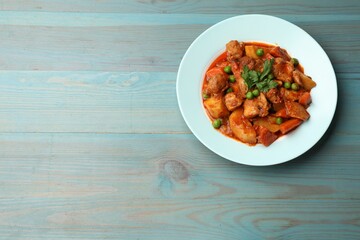 Delicious cooked stew on light blue wooden table, top view. Space for text