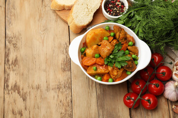 Delicious cooked stew served on wooden table, flat lay. Space for text