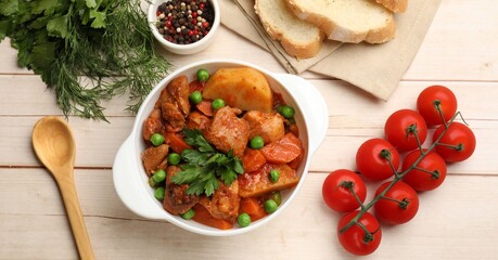 Delicious cooked stew served on light wooden table, flat lay