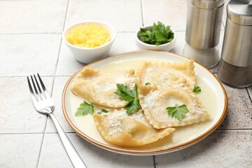 Delicious ravioli with cheese and parsley served on light tiled table, closeup