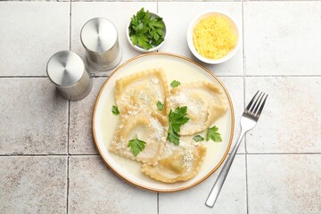 Delicious ravioli with cheese and parsley served on light tiled table, flat lay