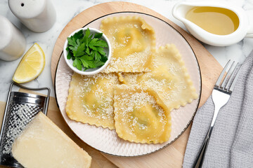 Delicious ravioli with cheese served on white marble table, flat lay