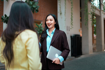 Asian businesswoman communicating outdoors with laptop
