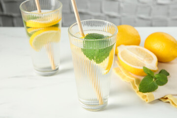 Refreshing water with lemons and mint on white marble table, closeup