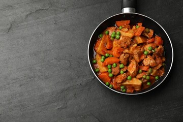 Delicious cooked stew in frying pan and ingredients on black table, top view. Space for text