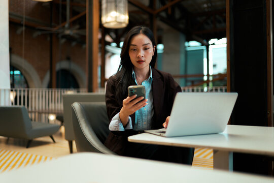 Asian businesswoman multitasking and working with smartphone and laptop