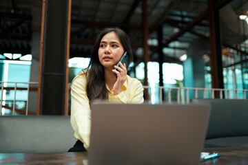 Young businesswoman talking on phone with laptop using remote work
