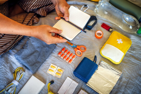 Emergency situation preparation - middle-aged woman with notebook by go-bag