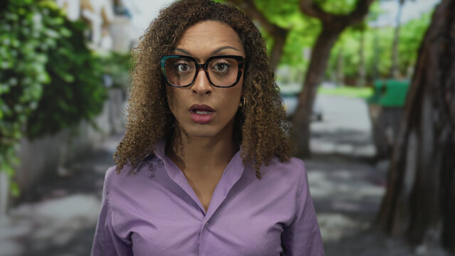 Woman straightens glasses and holds hands to head among green forest trees by path; stress frustration.