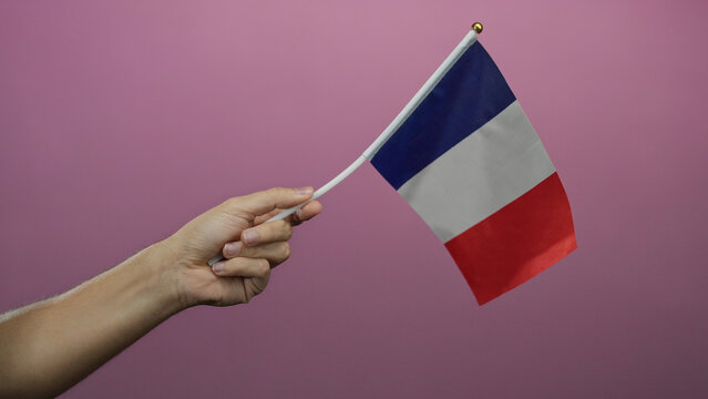 Man holding a small french flag with a pink background, highlighting the colors and national identity.