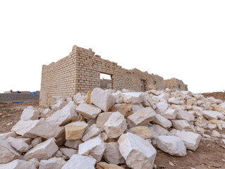 Ruined stone building beige brick wall broken window rubble pile abandoned construction outdoor arid landscape damaged structure historical site desolate mood