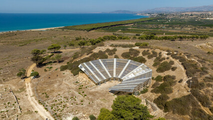 Aerial view of the theater of Eraclea Minoa. It's a ancient Greek theater located in the archaeological site of Cattolica Eraclea, in province of Agrigento, Sicily, Italy. In background is azure sea