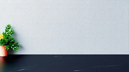 A small potted plant with green leaves and yellow flowers is placed on a dark surface in front of a light blue wall.