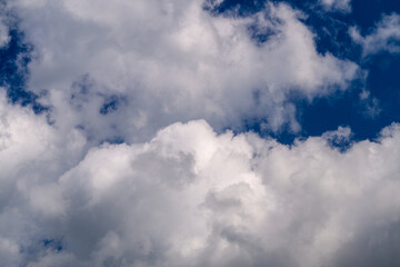 Fluffy white clouds are gracefully floating against a bright blue sky that inspires peace and joy