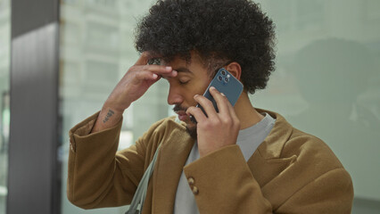 African american man multitasking on smartphone in urban city street, exhibiting a blend of focus and contemplation amid busy surroundings.