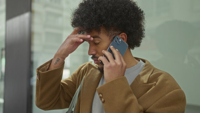 African american man multitasking on smartphone in urban city street, exhibiting a blend of focus and contemplation amid busy surroundings.