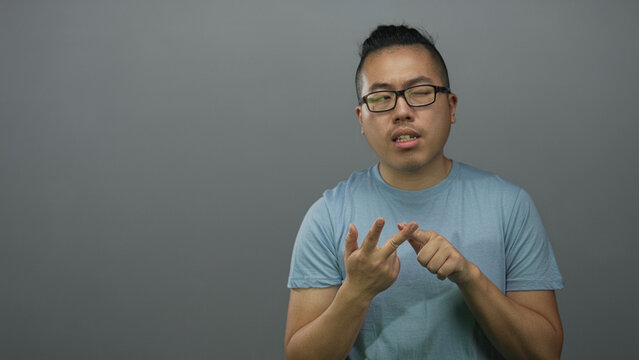 Man counting on fingers with hands visible against a gray studio wall, glasses and topknot hairstyle visible; concentration planning.