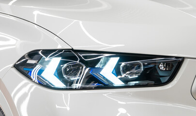 Close up detail on one of the LED Laser headlights modern white car. Exterior close up detail. Headlights of car. BI-LED Laser headlights of a modern white car. Front BI-LED headlight on sport car.