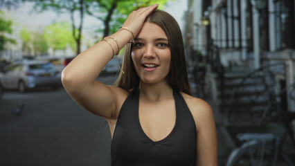 Caucasian teenage girl with bare shoulder and hand on head on bustling city street; surprise realization.