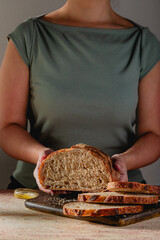 Baker Holding Sliced Sourdough Loaf on Dark Cutting Board