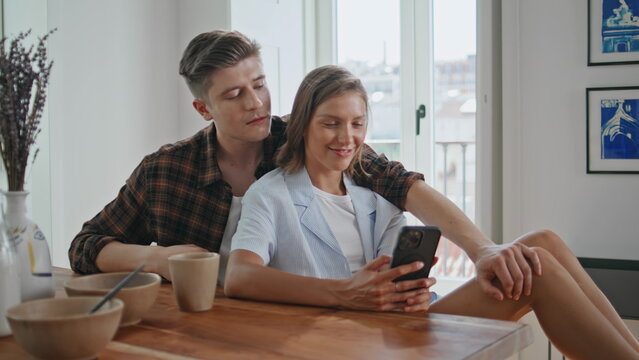Young family browsing smartphone in kitchen closeup. Girlfriend looking mobile