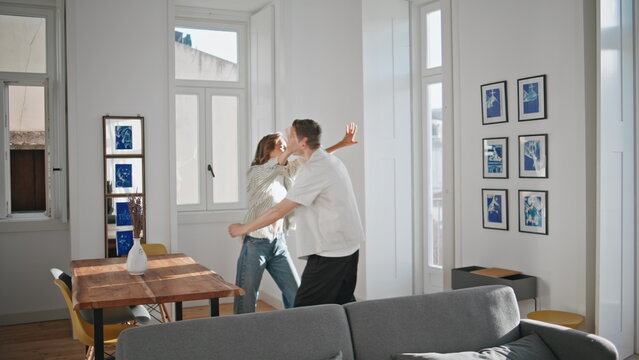 Couple hugging new apartment in sunlight. Man showing house key to girlfriend