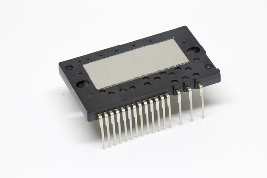 Three-quarter perspective of a black IPM (Intelligent Power Module) with circular alignment holes, brushed metal plate, and long connector leads, isolated on white