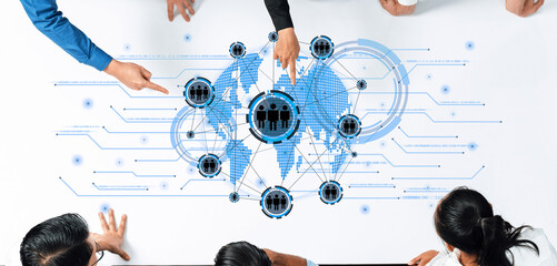 Diverse professionals collaborate over a digital world map, pointing at connected figures, symbolizing teamwork, innovation, and strategic planning in business. Trope