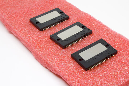 Three identical IPM (Intelligent Power Module) units arranged on pink antistatic foam, showing metal heat-spreaders and connector pin banks