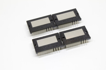 Group of four IPM (Intelligent Power Module) packages arranged in a two-by-two grid on a white background, showing metal heat spreaders and multi-pin leads