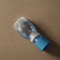 Empty plastic eye drop bottle with blue cap on brown surface
