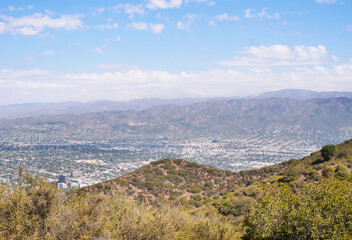 Fototapeta premium Skyline of Burbank as seen from the top of Cahuenga Peak at Wisdom Tree hiking trail during a summer season in Los Angeles, California, USA