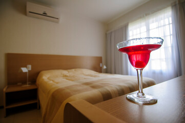 Red cocktail glass on bedside table in hotel room
