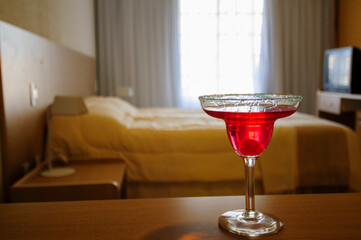 Red cocktail glass on bedside table in hotel room