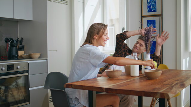 Cheerful couple having fun during home breakfast. Happy man playing with food