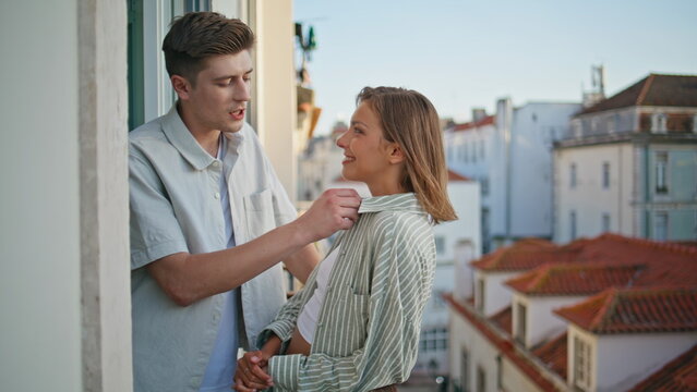 Smiling couple city rooftops enjoying date. Handsome man flirting on balcony