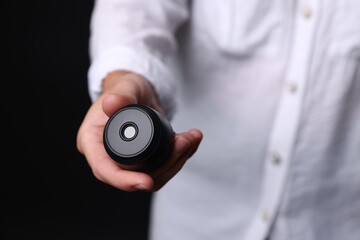 Young woman with hidden spy camera on black background, closeup
