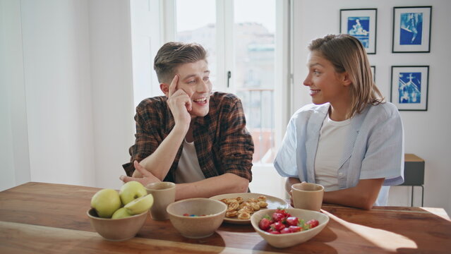 Joyful spouses breakfasting morning together. Smiling man talking relaxed wife