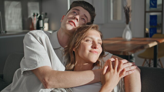 Married couple embracing home in sunlight. Closeup loving partners communicating
