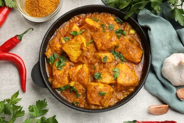 Chicken tikka masala with spices on grey table, flat lay
