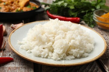 Cooked rice, chicken tikka masala and spices on wooden table, closeup