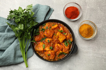 Chicken tikka masala with spices on grey table, flat lay