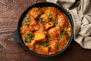 Chicken tikka masala with parsley on wooden table, top view